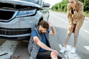 woman driver feeling sorry about injured man suffering on the pedestrian crossing near the car after the road accident